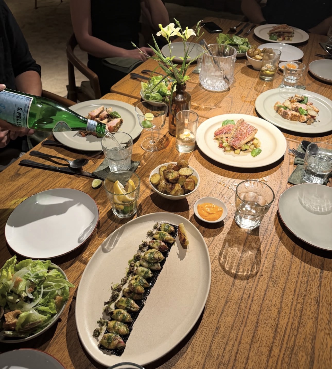 A shared dinner with fresh dishes and drinks on a wooden table