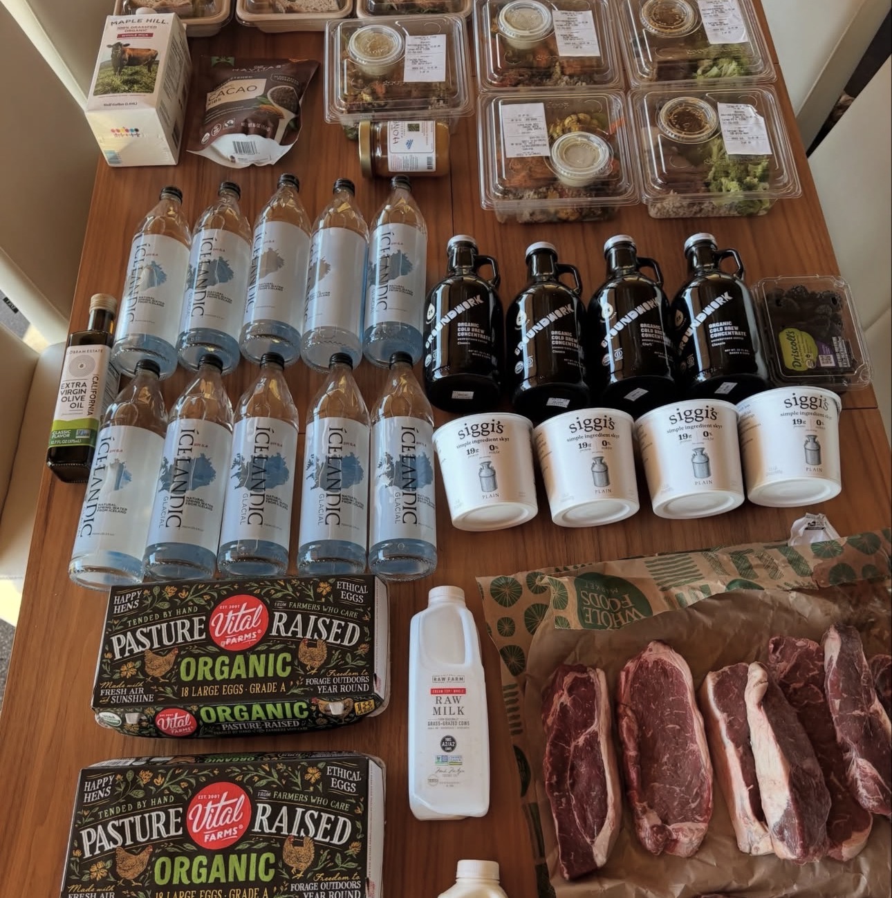 Groceries and prepared meals laid out together on a kitchen table