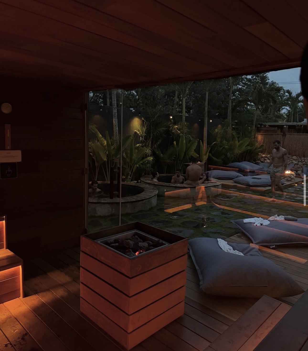A warm wooden sauna overlooking outdoor plunge pools and a tropical garden