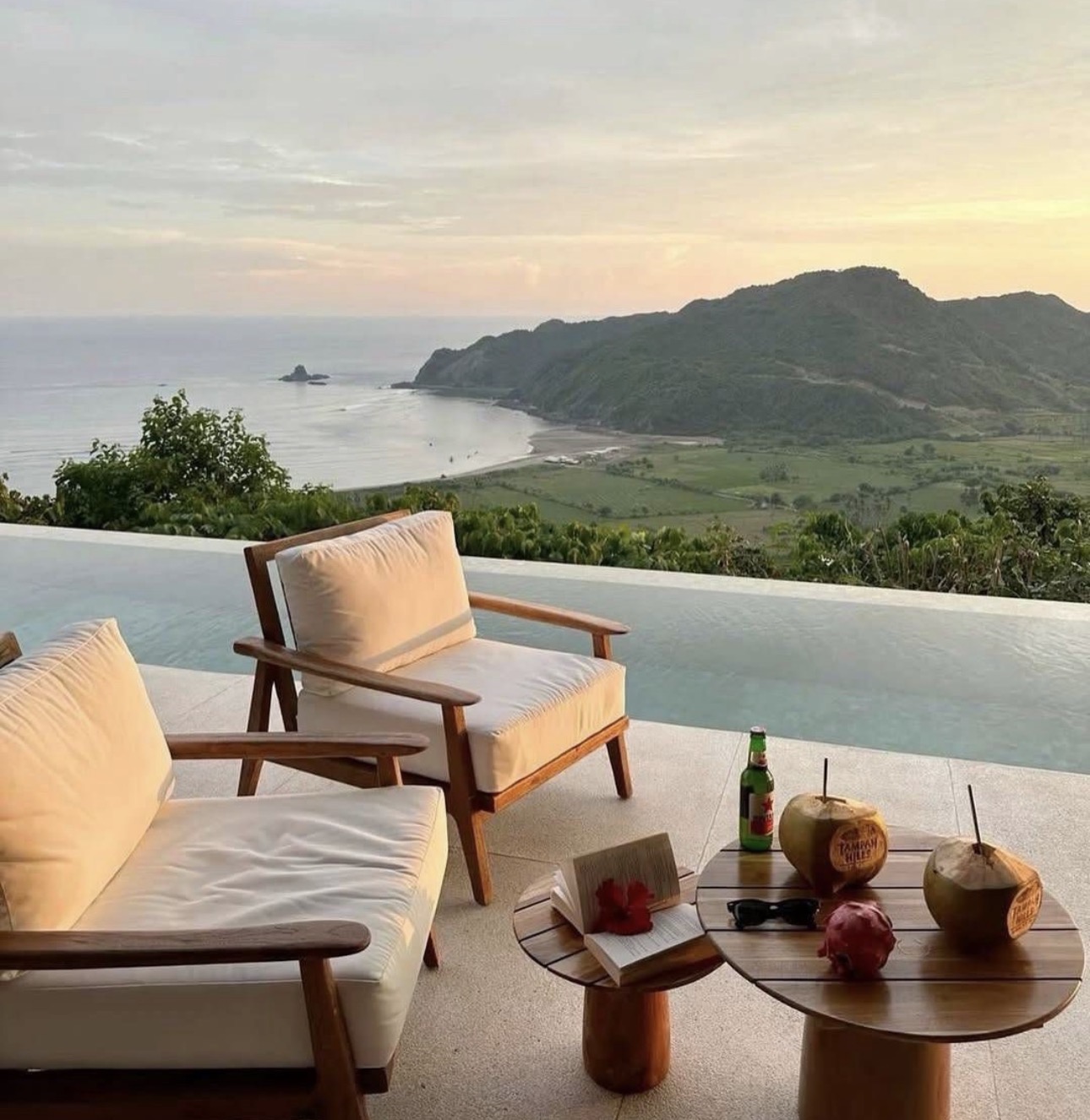 Two chairs beside an infinity pool at sunset